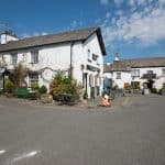 Hawkshead Suites exterior. Charming outdoor view of Hawkshead Suites in a picturesque village setting, featuring traditional white cottages.